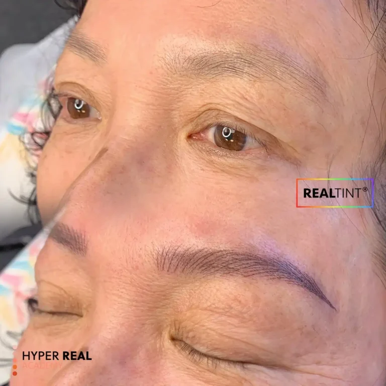 Close-up nano brows PMU result with ultra-fine hair-like strokes and natural brown pigment. RealTint® and Hyper Real Academy branding for permanent makeup.