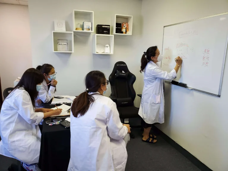 PMU training classroom at Hyper Real Academy with treatment beds and magnifying lamps. REALTINT® branding for nano brows, lip blush, SMP training.