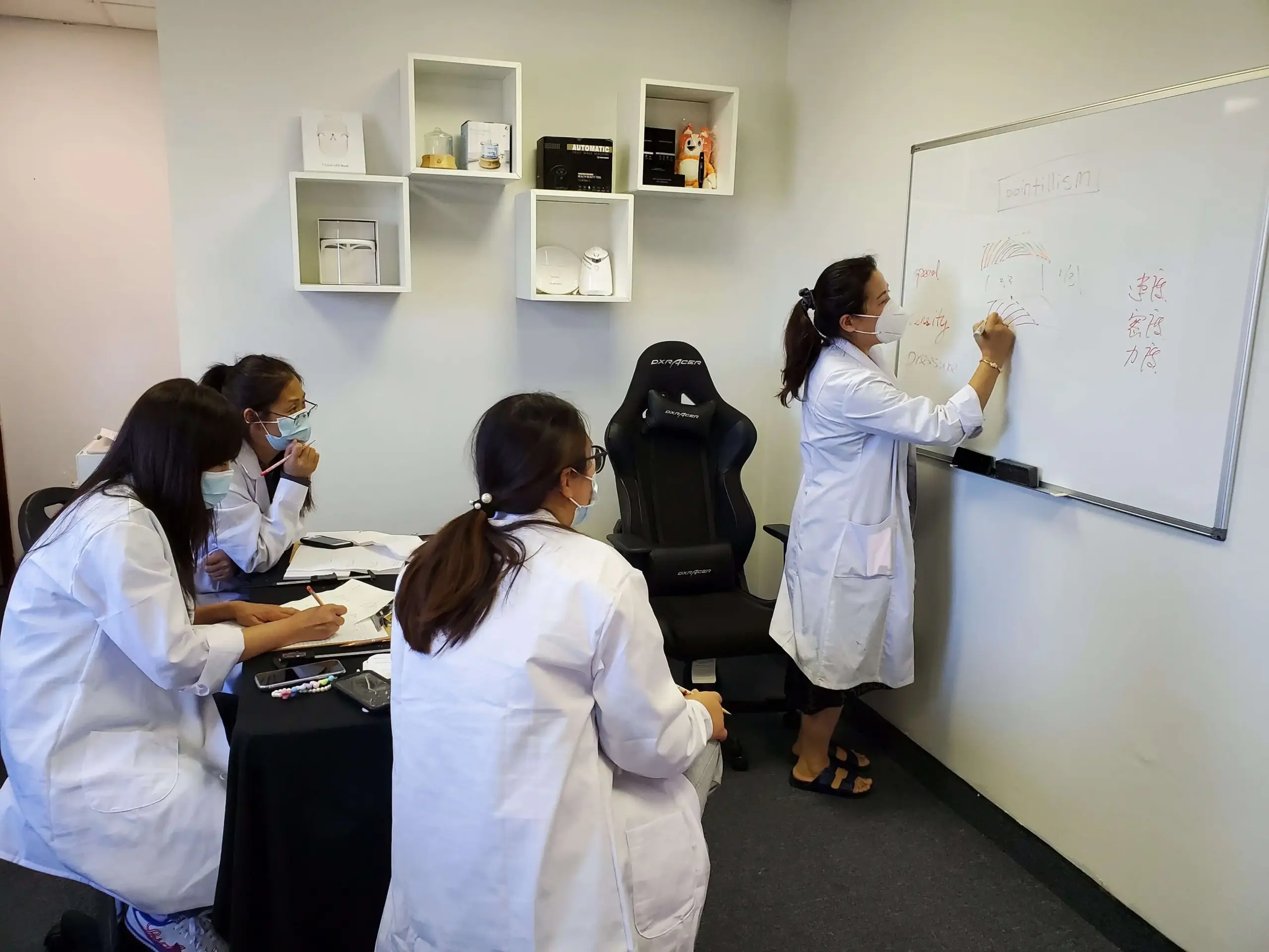 PMU training classroom at Hyper Real Academy with treatment beds and magnifying lamps. REALTINT® branding for nano brows, lip blush, SMP training.