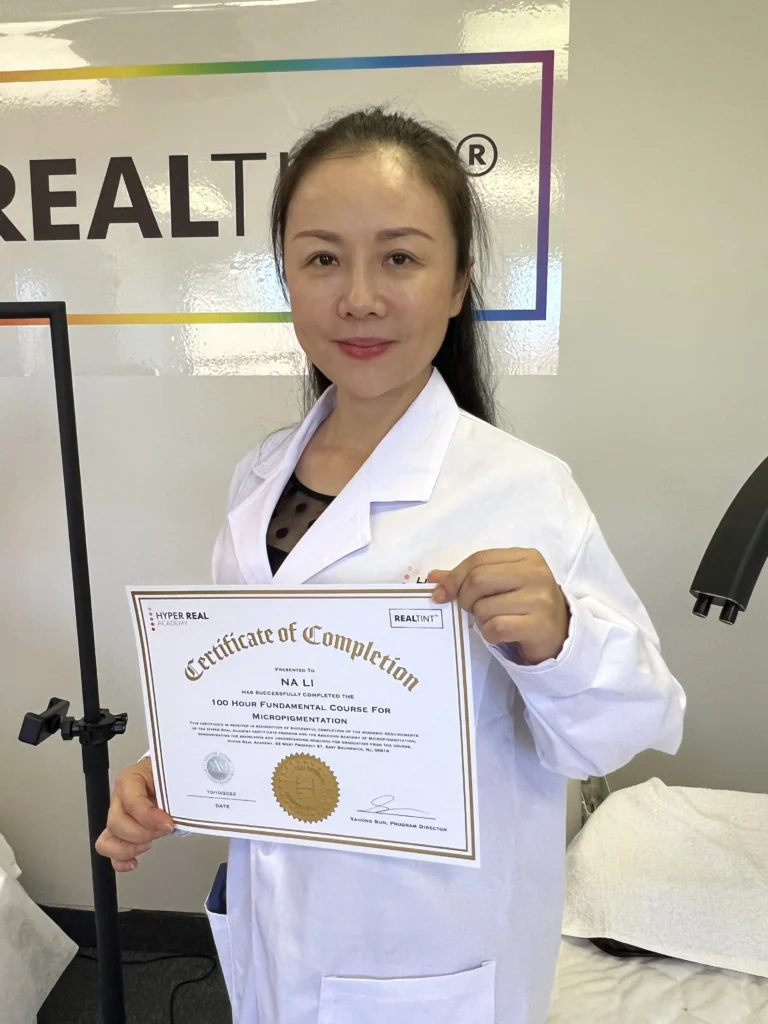 Hyper Real Academy RealTint permanent makeup training graduate holding micropigmentation certificate.