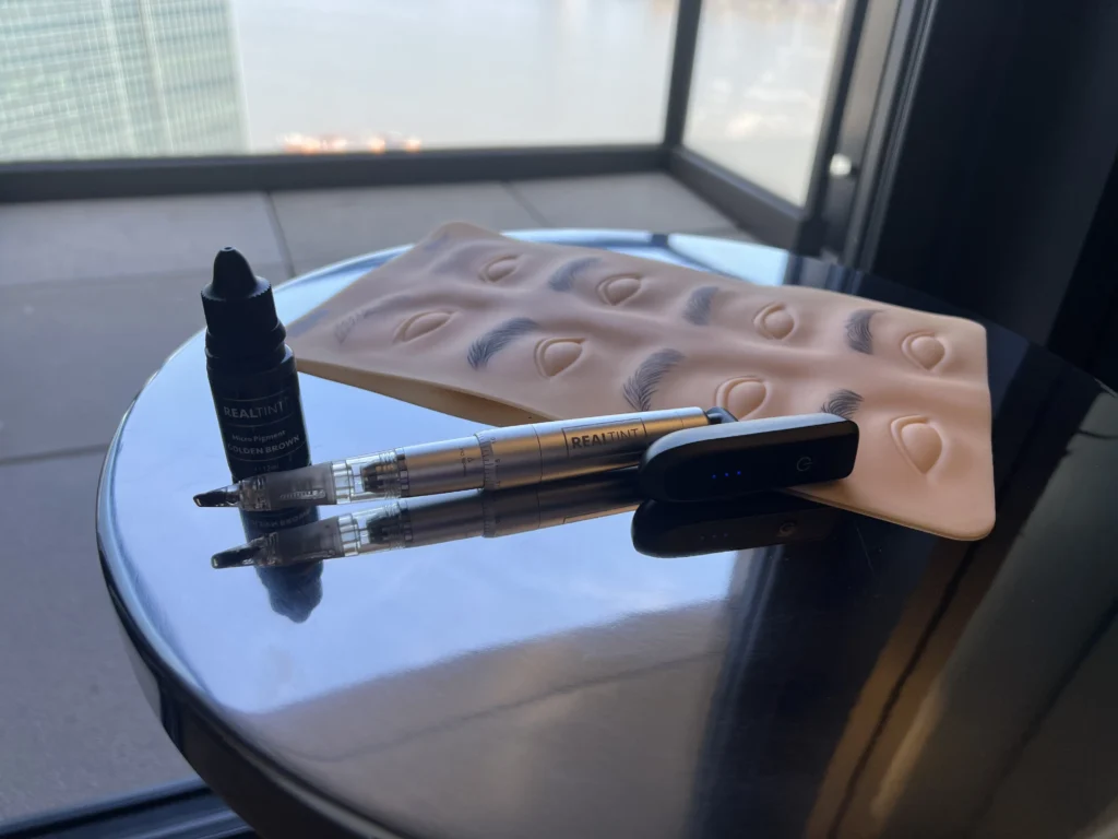 RealTint PMU training setup with Golden Brown pigment, nano brow pen, and practice skin with hair strokes.
