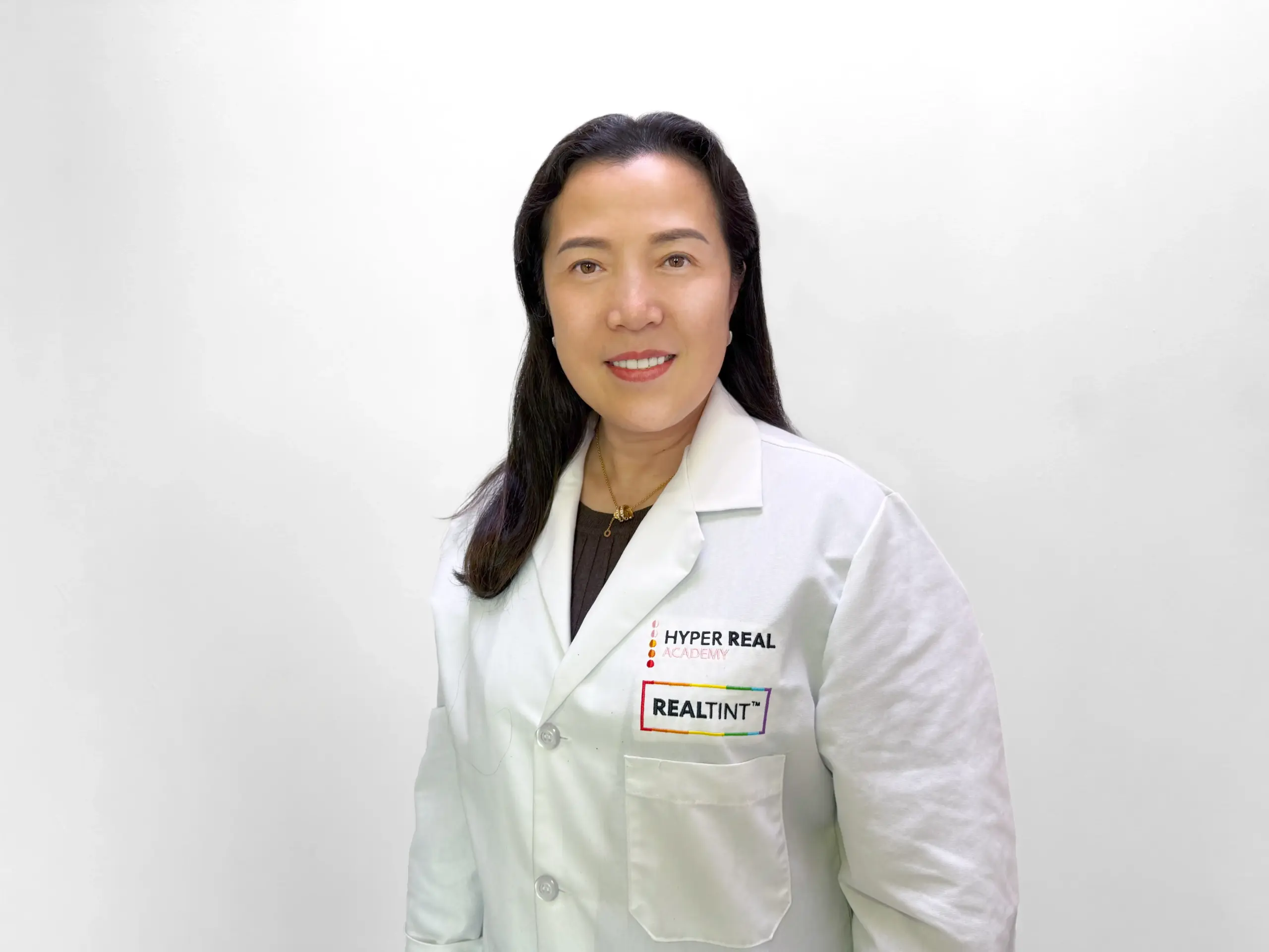 Anna, Hyper Real Academy PMU instructor in white lab coat with RealTint logo for permanent makeup training and demonstration.
