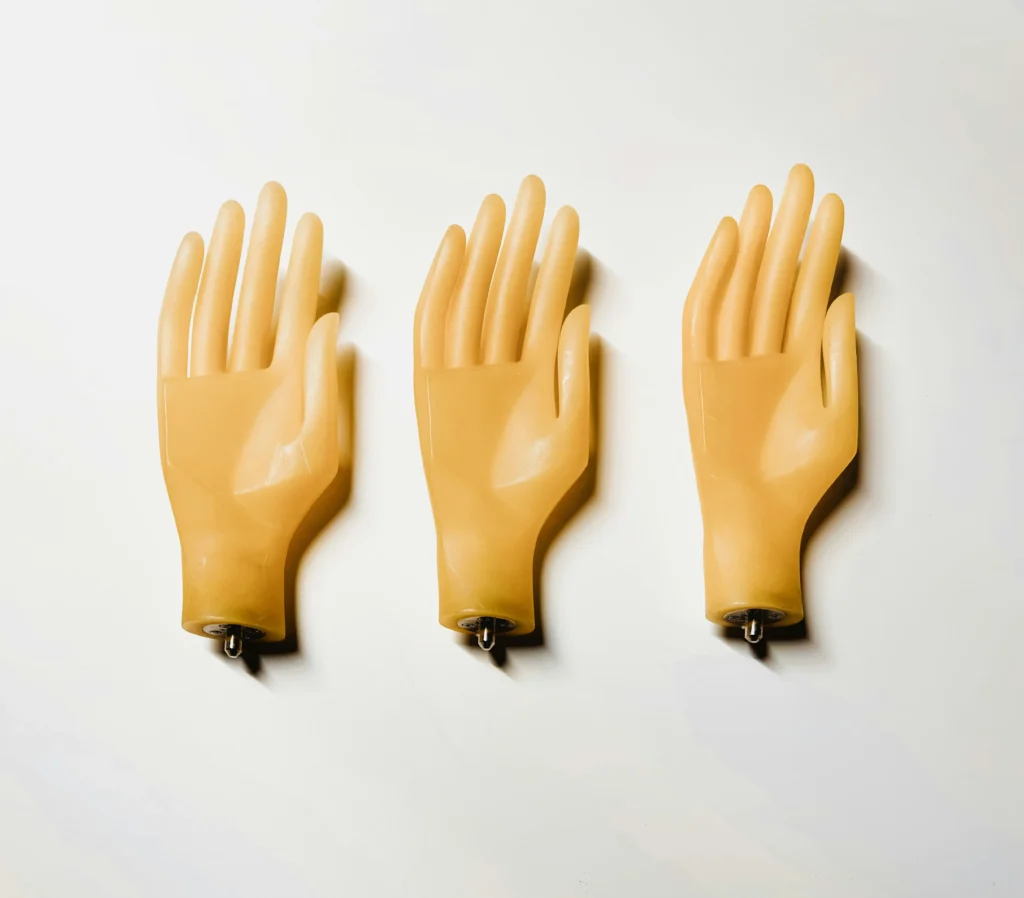 Three tan silicone practice hands on white background for PMU training, eyeliner, nano brows, and lip blush demonstration.