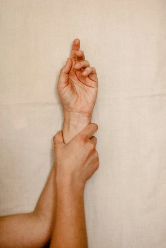 PMU training hands demonstrating stability for nano brows and eyeliner. Wrist grip on beige background.