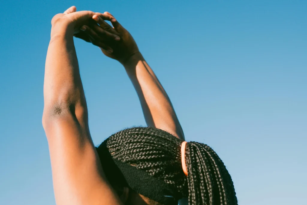 Woman stretching arms up blue sky, Hyper Real Academy permanent makeup training.