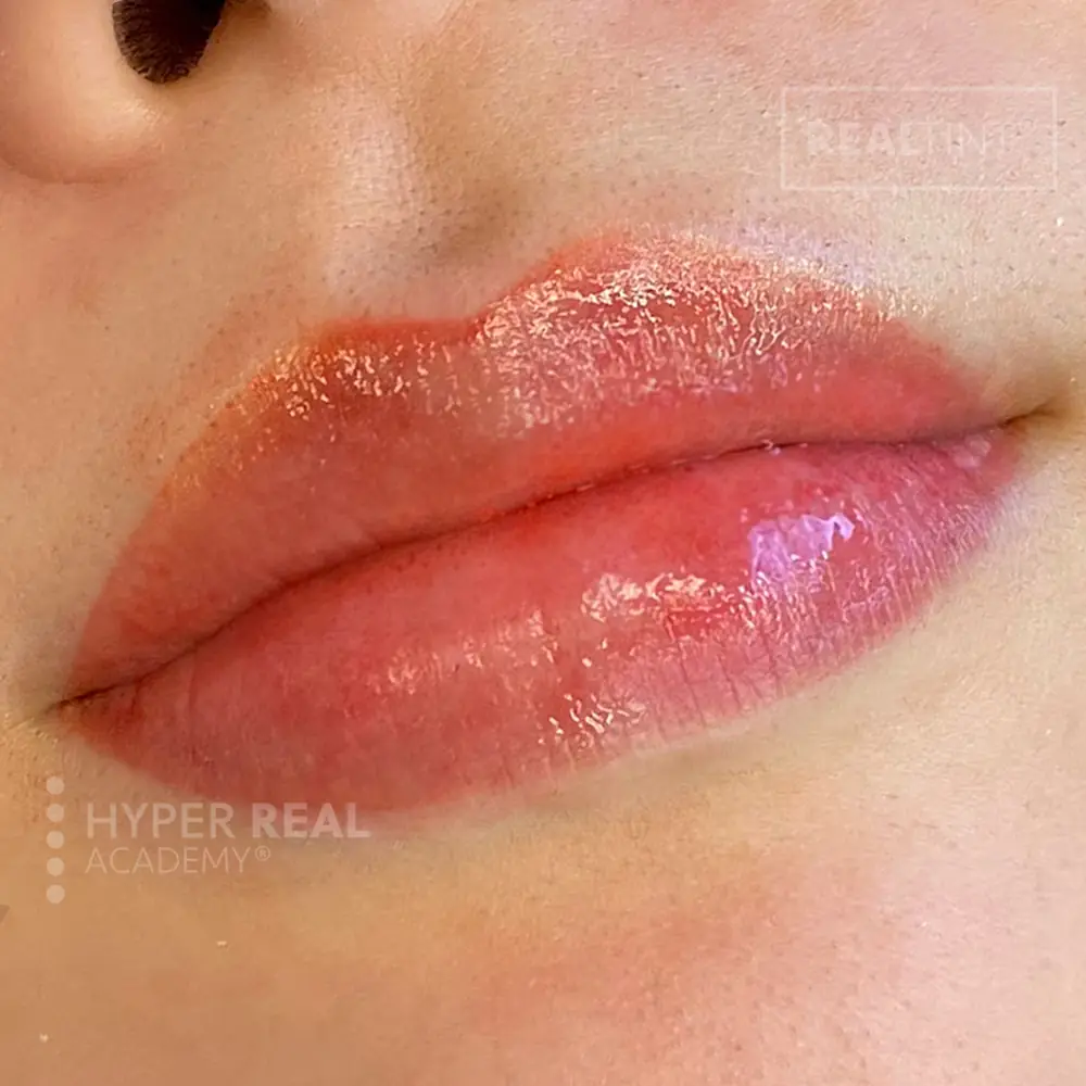 Pointillism lip blush - pixelated dot technique creating soft lip color. Individual needle punctures visible showing tattooing process rather than lipstick application.