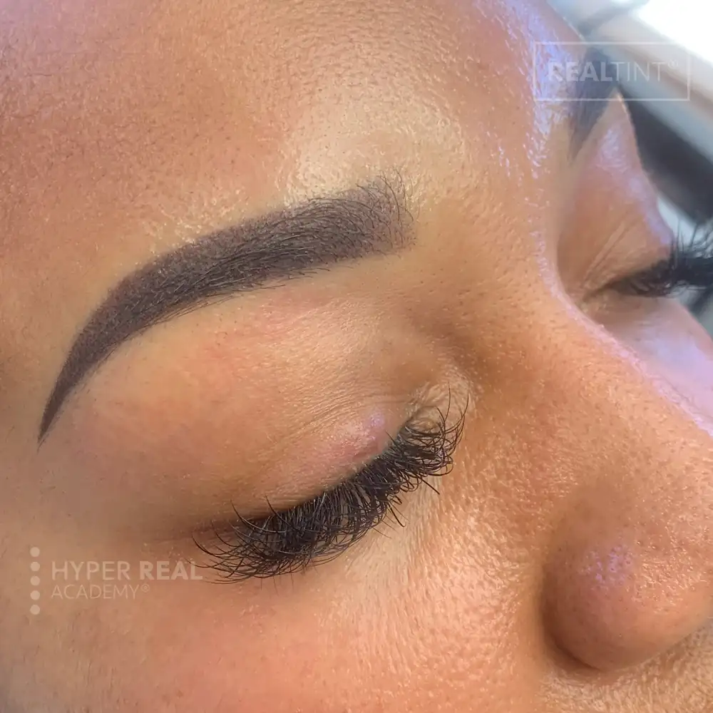 Eyeliner PMU with subtle lash line enhancement and delicate micro-wing. Soft powder effect with natural pigment saturation. Watermark 'REALIST' visible.