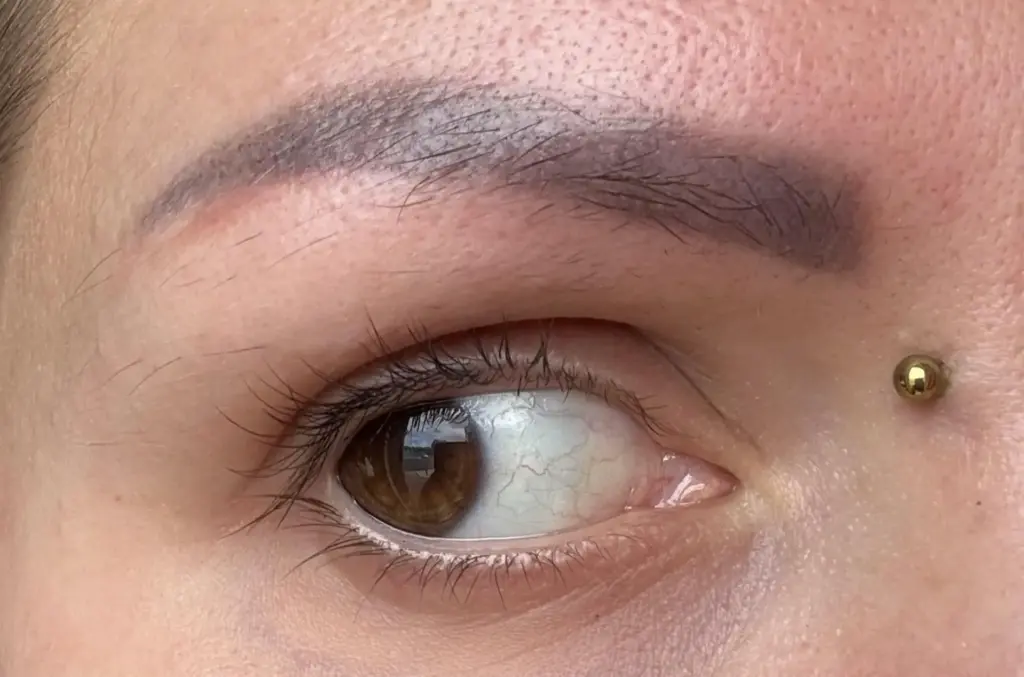 close up of a misalisgned permanent makeup eyebrow
